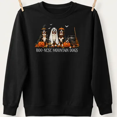 Illustrative Halloween scene featuring Boo Nese Mountain Dogs in witch costumes with pumpkins — printed on a unisex sweatshirt