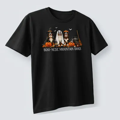 Illustrative Halloween scene featuring Boo Nese Mountain Dogs in witch costumes with pumpkins — printed on a unisex t-shirt (angled view)