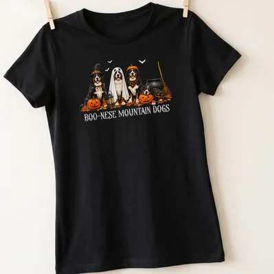 Illustrative Halloween scene featuring Boo Nese Mountain Dogs in witch costumes with pumpkins — printed on a women's shirt