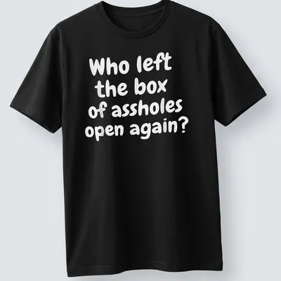 Funny T-shirt with text asking who left the box of assholes open again, against a white background.