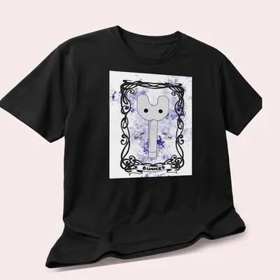Whimsical illustration of a key-like character with 'BUNNIES' text in purple and gray tones — printed on a unisex t-shirt (angled view)
