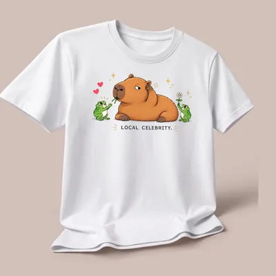 Kawaii style capybara surrounded by frog fans with text 'LOCAL CELEBRITY.' — printed on a unisex t-shirt (angled view)
