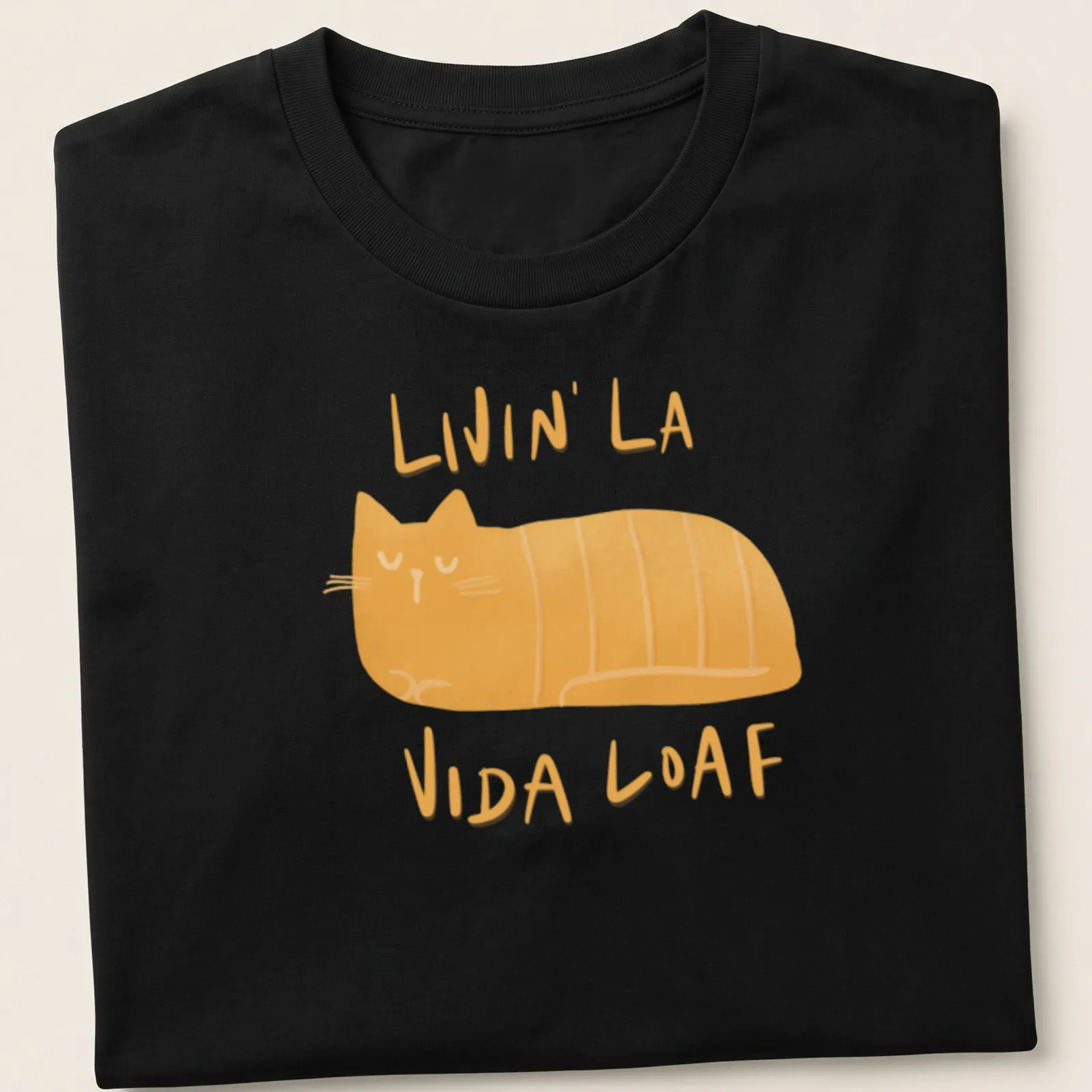 Kawaii illustration of a loafing cat with text 'Livin' La Vida Loaf' in orange and cream. — printed on a unisex t-shirt