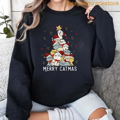 Cartoon cats in Santa hats with Merry Catmas text on a festive shirt. — printed on a sweatshirt