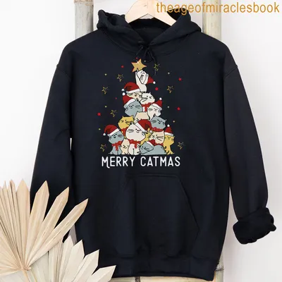 Cartoon cats in Santa hats with Merry Catmas text on a festive shirt. — printed on a unisex hoodie