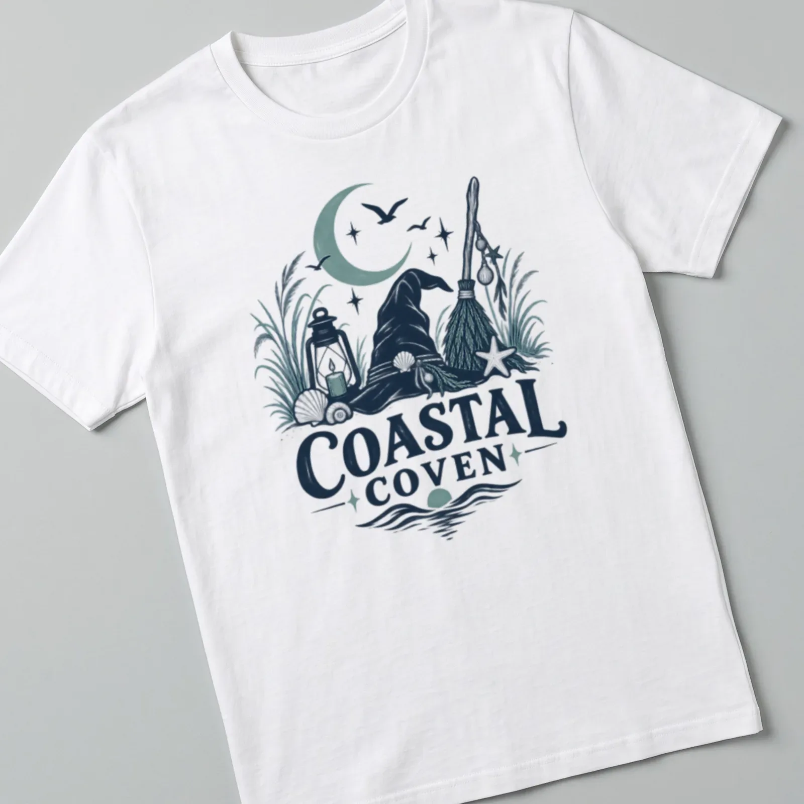 Vintage illustrated Coastal Coven t-shirt with witch hat and coastal motifs — printed on a unisex t-shirt