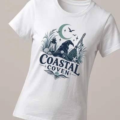 Vintage illustrated Coastal Coven t-shirt with witch hat and coastal motifs — printed on a women's shirt
