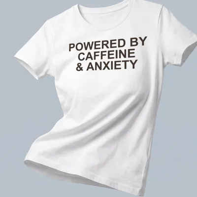 Bold typography t-shirt with the phrase 'Powered By Caffeine & Anxiety' in brown — printed on a women's shirt