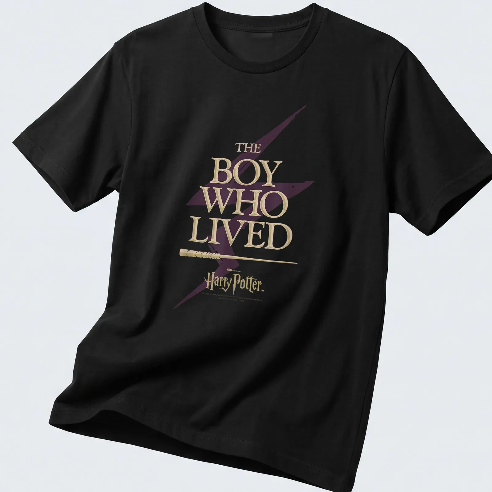 Bold lettering of 'The Boy Who Lived' with a lightning bolt motif in gold and purple — printed on a unisex t-shirt
