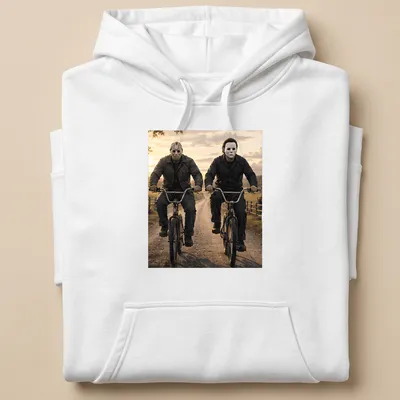 Realistic depiction of Jason Voorhees and Michael Myers riding bikes in dark colors — printed on a unisex hoodie