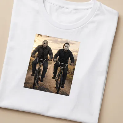 Realistic depiction of Jason Voorhees and Michael Myers riding bikes in dark colors — printed on a women's shirt