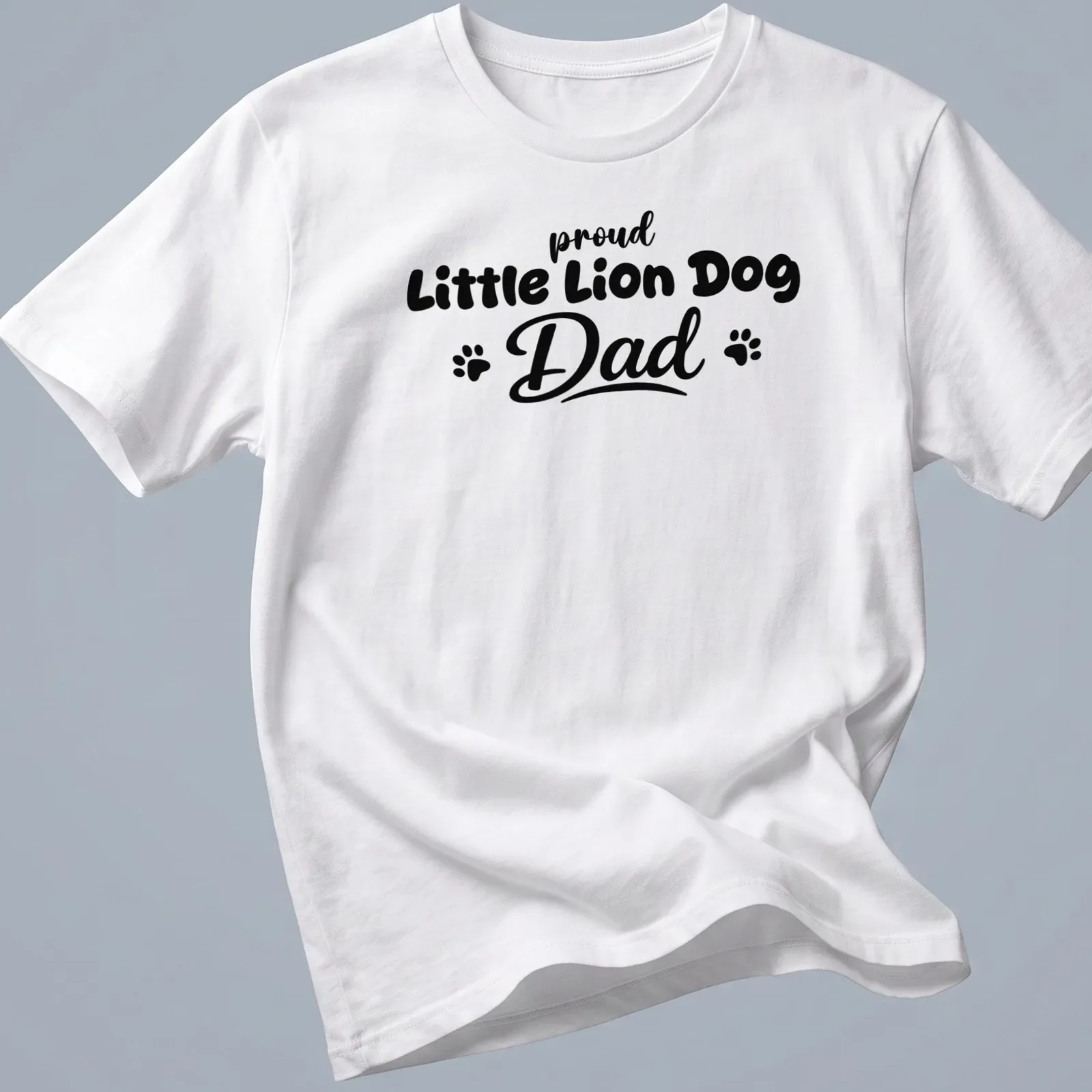 Bold typography t-shirt stating 'proud Little Lion Dog Dad' with playful Little Lion Dog illustration — printed on a unisex t-shirt
