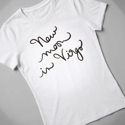 Handwritten script design reading 'New moon in Virgo' in black text — printed on a women's shirt