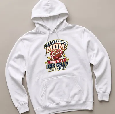 Bold, colorful text reads 'Quarterback Mom: Surviving One Snap at a Time' with football imagery — printed on a unisex hoodie