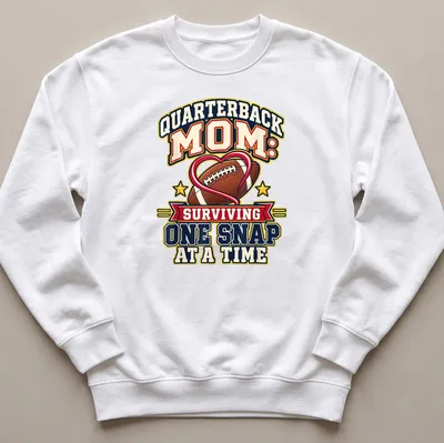 Bold, colorful text reads 'Quarterback Mom: Surviving One Snap at a Time' with football imagery — printed on a unisex sweatshirt