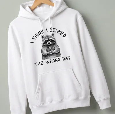 Detailed line-art of a raccoon holding a coffee cup with humorous text about seizing the day — printed on a unisex hoodie