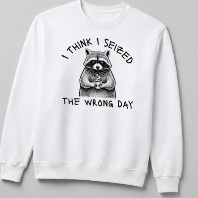 Detailed line-art of a raccoon holding a coffee cup with humorous text about seizing the day — printed on a unisex sweatshirt