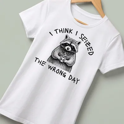 Detailed line-art of a raccoon holding a coffee cup with humorous text about seizing the day — printed on a women's shirt