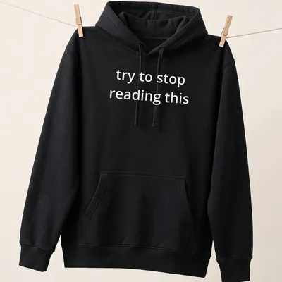 Bold white text reads 'try to stop reading this' on a black — printed on a unisex hoodie