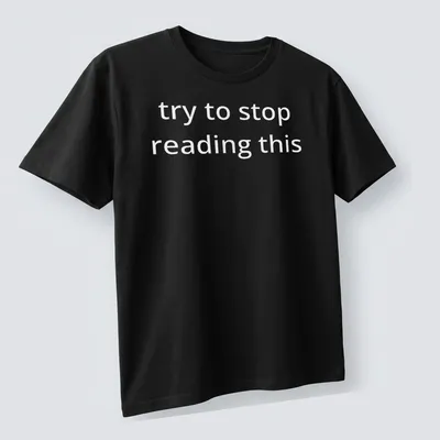 Bold white text reads 'try to stop reading this' on a black — printed on a unisex t-shirt (angled view)