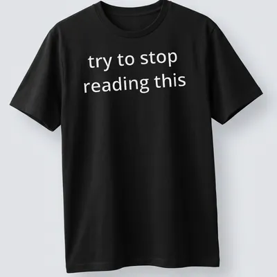 Bold white text reads 'try to stop reading this' on a black — printed on a unisex t-shirt