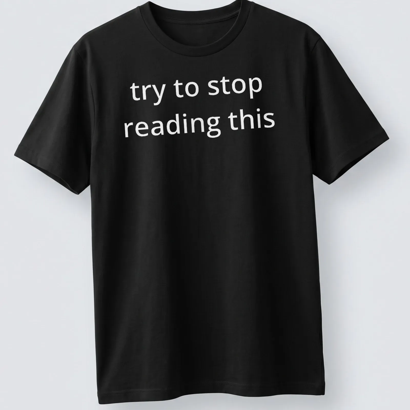 Bold white text reads 'try to stop reading this' on a black — printed on a unisex t-shirt