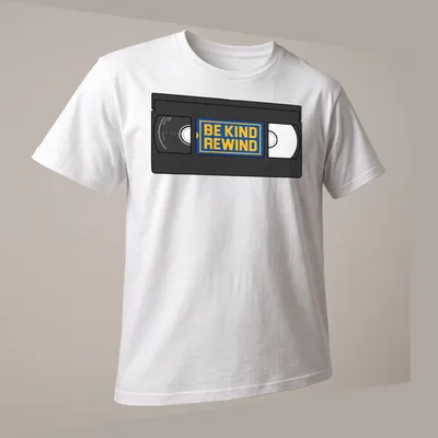 Vintage VHS tape graphic with 'Be Kind Rewind' text in black, yellow, blue, and white. — printed on a unisex t-shirt (angled view)